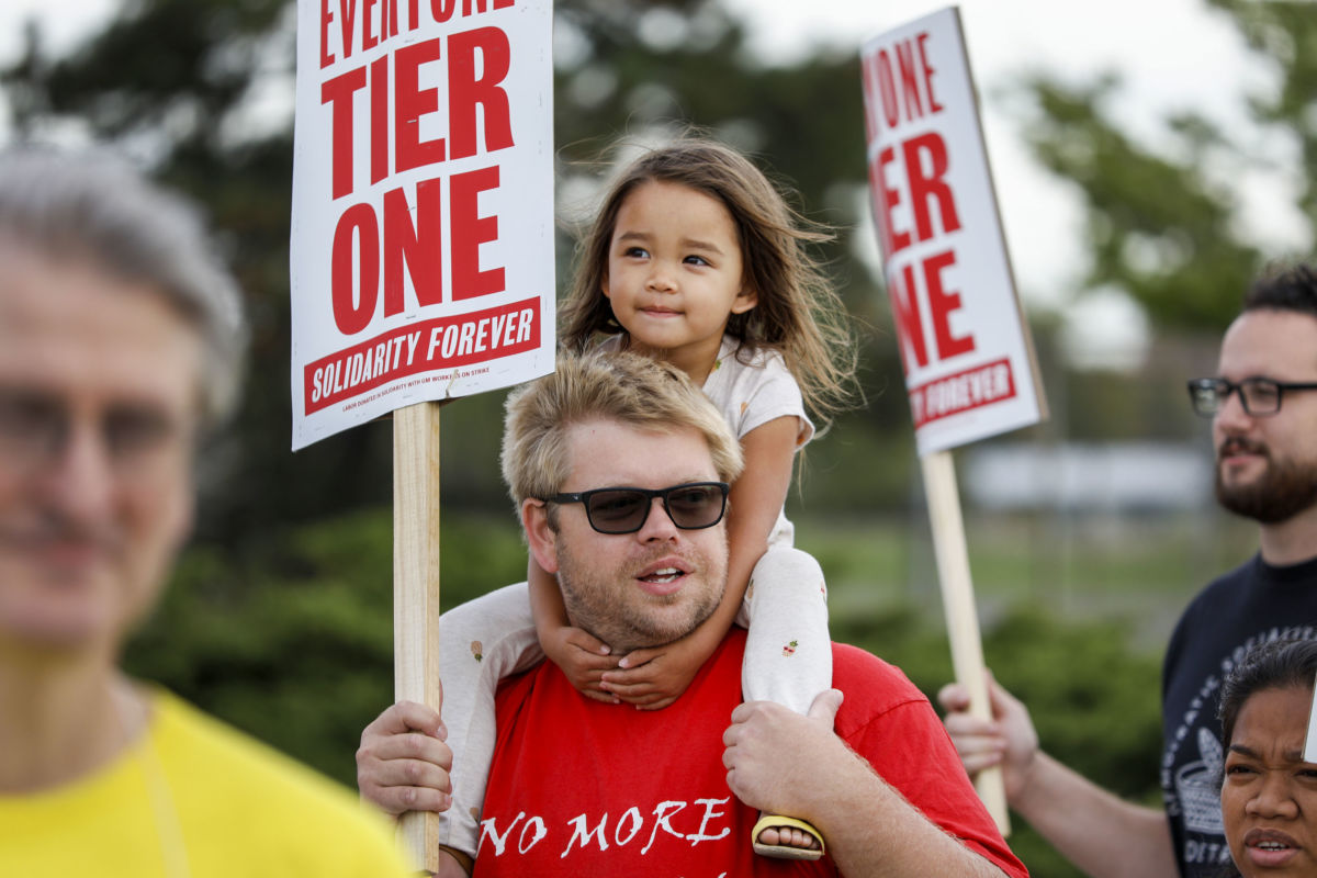 A man protesting man holds a little girl on his shoulders