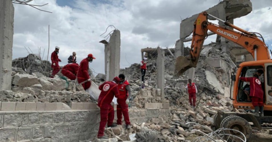 Rescue workers search for victims amongst the rubble of a building that was destroyed in an alleged Saudi-led airstrike targeting a Houthi-held detention center.