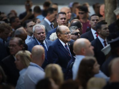 Rudy Giuliani stands in the center of a large crowd of people