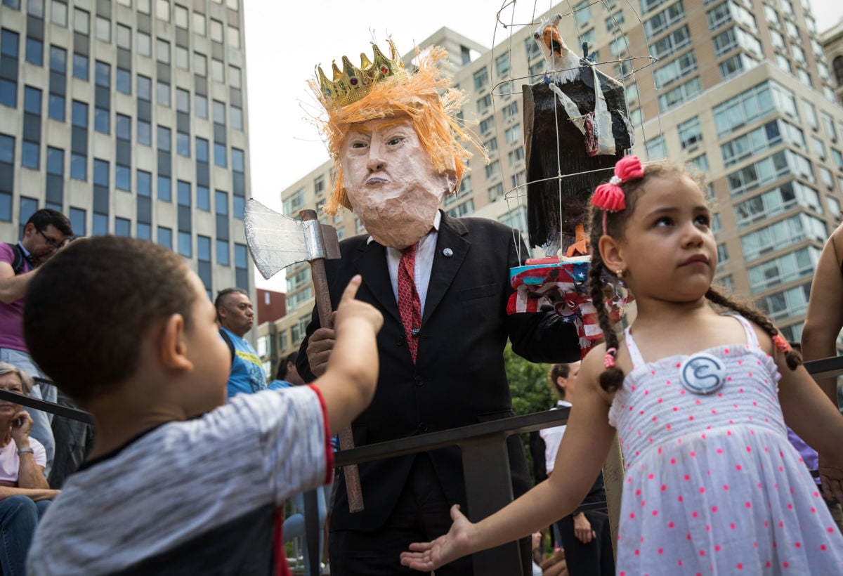 A man dressed to resemble President Trump interacts with children as activists rally