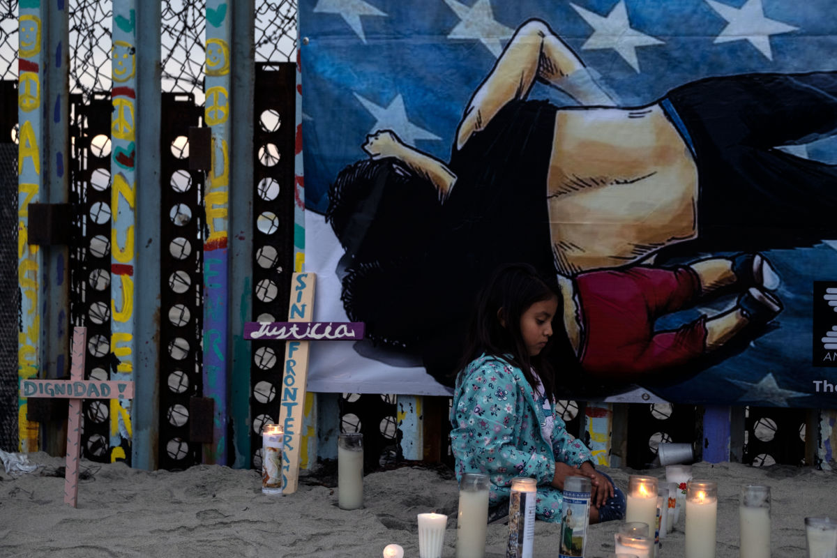 A young girl lights candles in front of a painting of a father holding his dauther