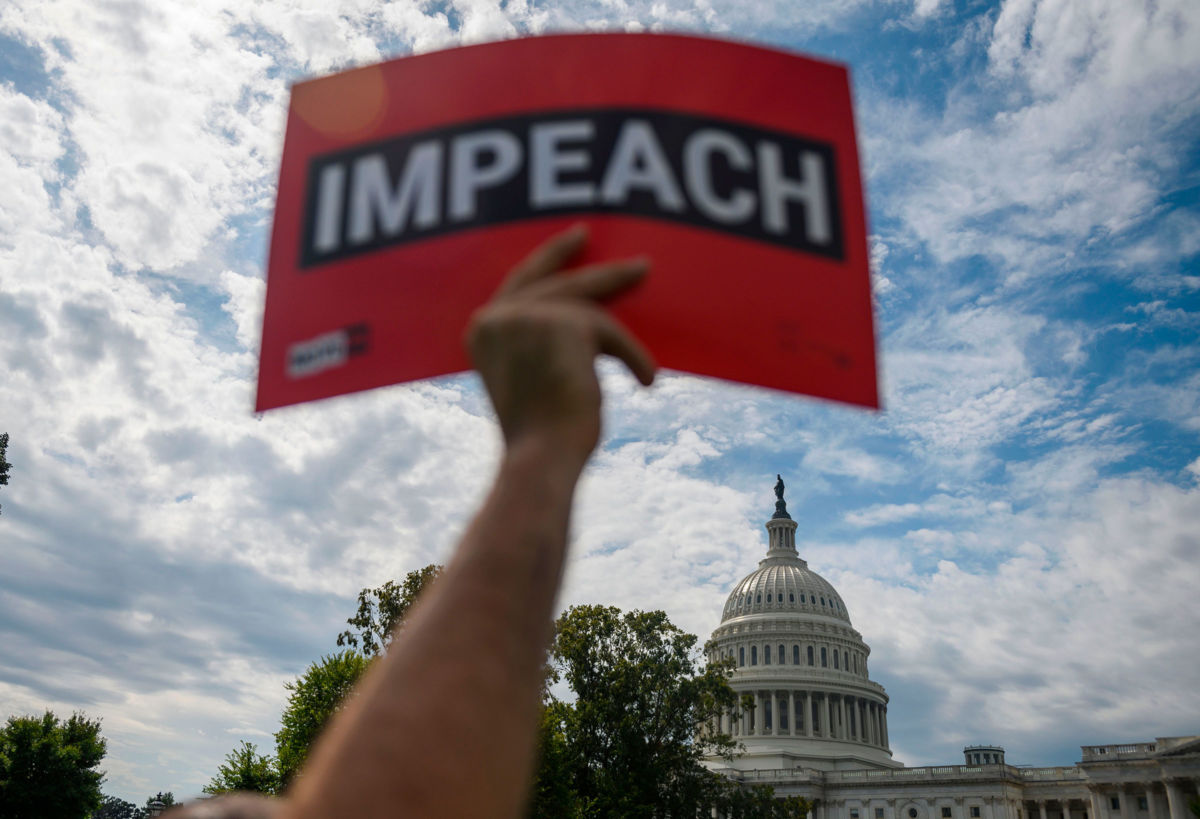 A protester holds up a sign reading Impeach outside the US Capitol building