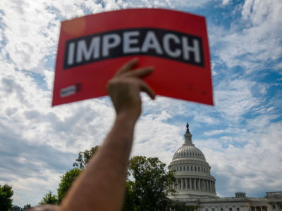 A protester holds up a sign reading Impeach outside the US Capitol building