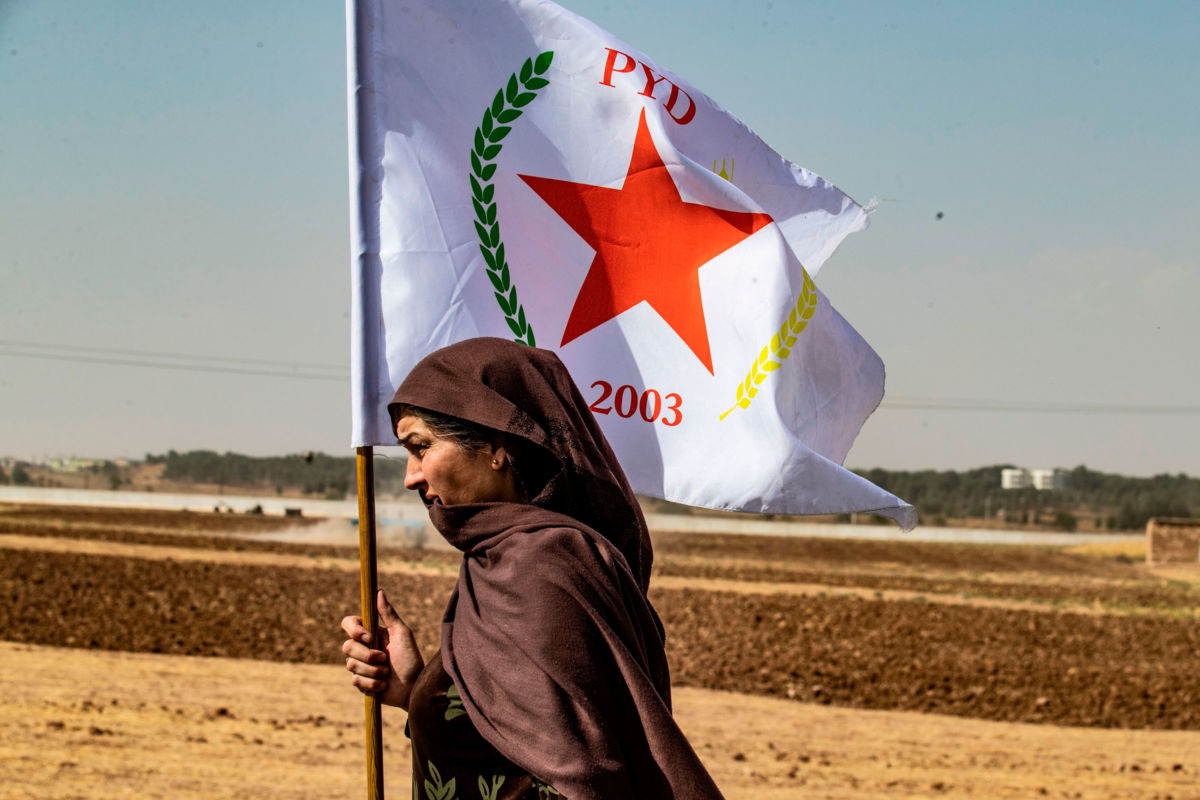 A Syrian Kurdish woman waves the flag of the Democratic Union Party (PYD) during a demonstration against Turkish threats near the town of Tel Arqam in Syria's Hasakeh province near the Turkish border on October 6, 2019.