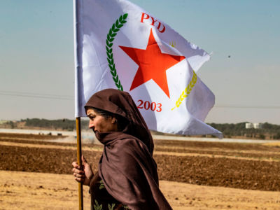 A Syrian Kurdish woman waves the flag of the Democratic Union Party (PYD) during a demonstration against Turkish threats near the town of Tel Arqam in Syria's Hasakeh province near the Turkish border on October 6, 2019.