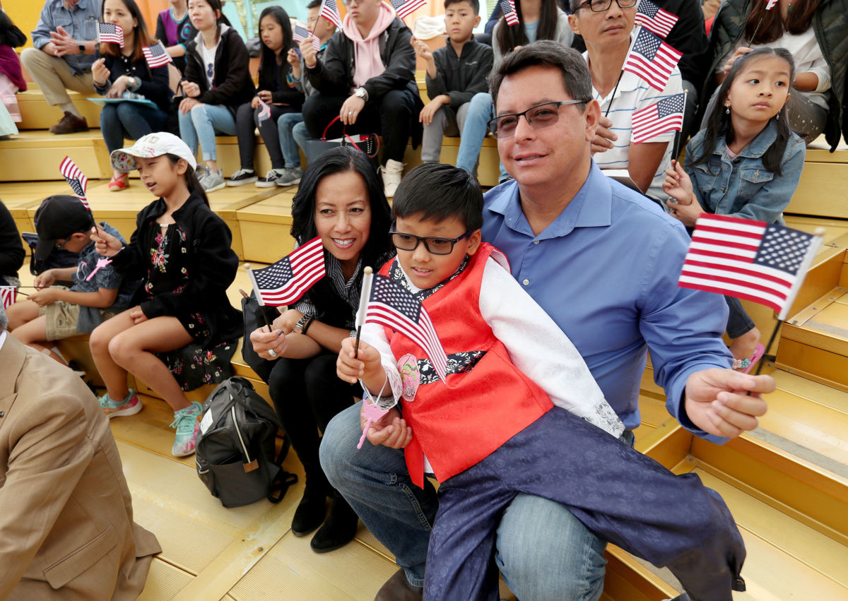 A father sits with his two children, all of whom are waving tiny US flags