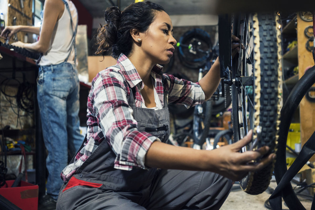 A woman repairs a bike tire while in a shop