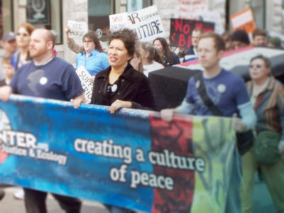 Several people march in a line while carrying a banner