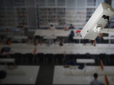 A surveillance camera is pointed down at a school library full of students