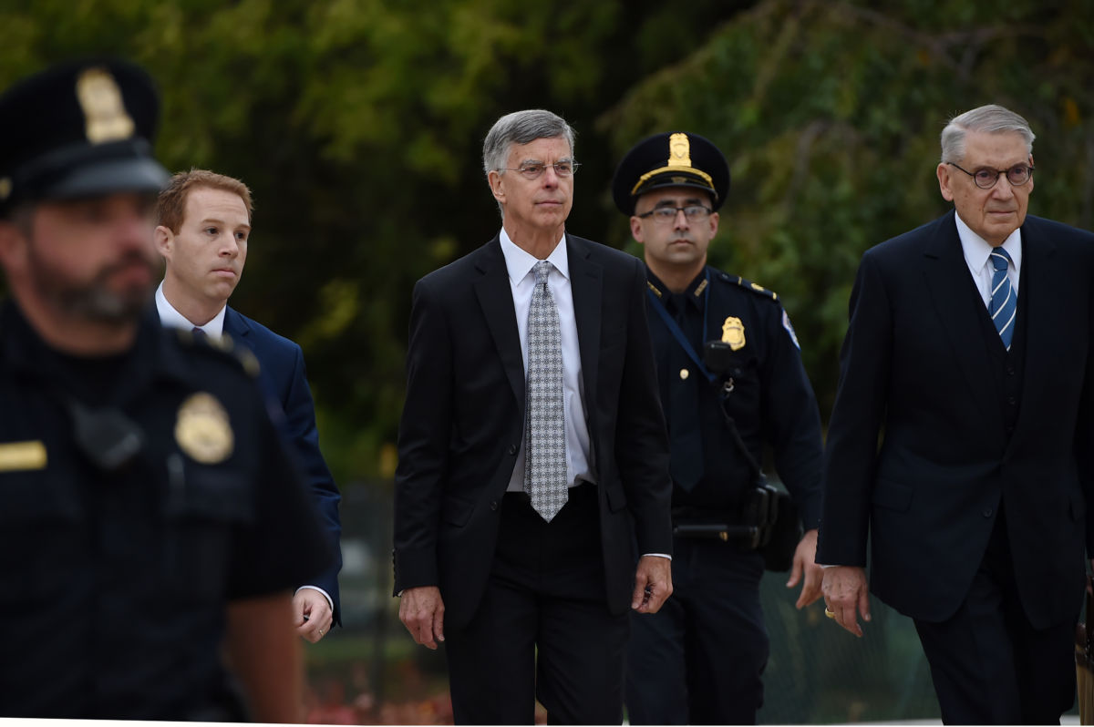 Bill Taylor walks outside, flanked by uniformed police officers