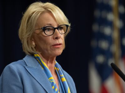 Betsy DeVos stands in front of a microphone