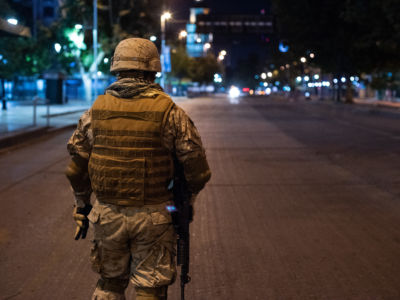A soldier stands in the middle of a vacated street