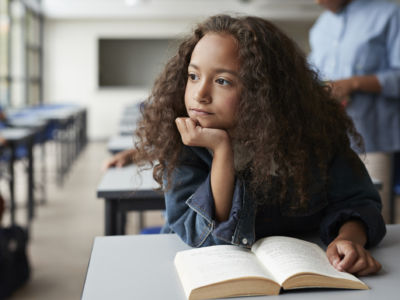 A girl pauses while reading a book to look away and think