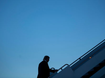 A silhouetted Donald Trump boards air force one