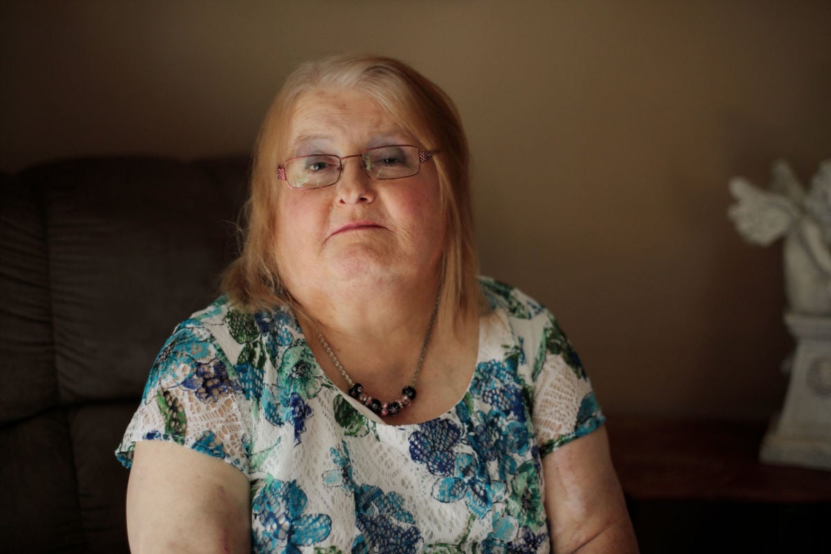 A woman in a blue floral blouse looks into the camera