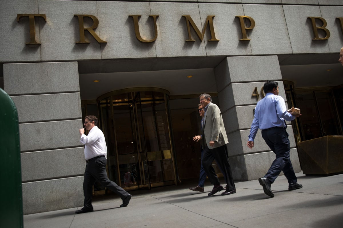 Businessmen walk past the Trump Building in the Financial District, August 21, 2018, in New York City.