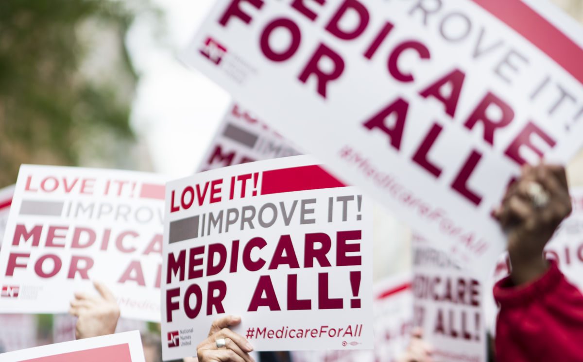 Members of National Nurses United union members wave "Medicare for All" signs