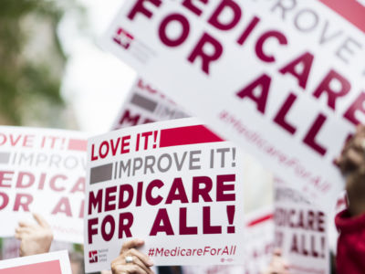 Members of National Nurses United union members wave "Medicare for All" signs