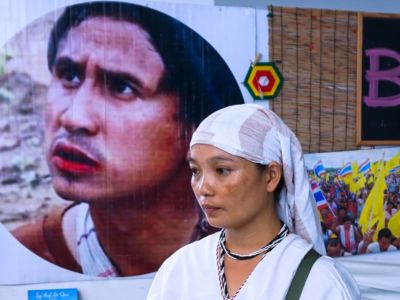 Pinnapha Phrueksapan, widow of ethnic Karen leader Por Cha Lee Rakcharoen stands beside the portrait of her late husband following a ceremony in Bangkok on September 16, 2019.