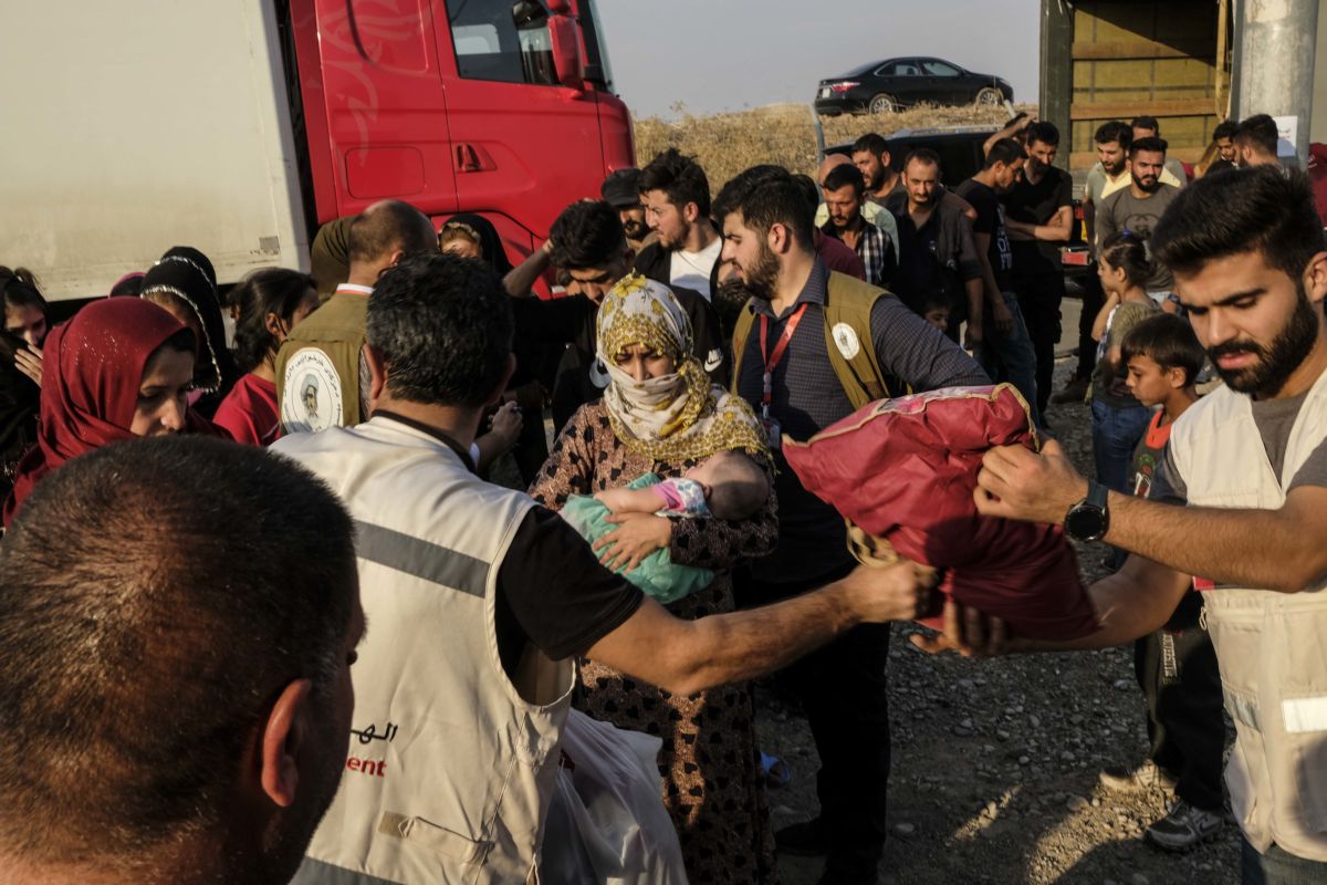 Syrian refugees fleeing the Turkish incursion in Rojava receive bedding materials as they arrive at the Badarash IDPs camp on October 17, 2019, in Dohuk, Iraq.