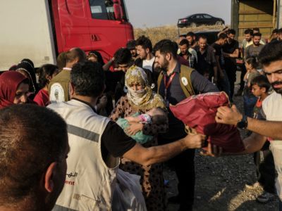 Syrian refugees fleeing the Turkish incursion in Rojava receive bedding materials as they arrive at the Badarash IDPs camp on October 17, 2019, in Dohuk, Iraq.