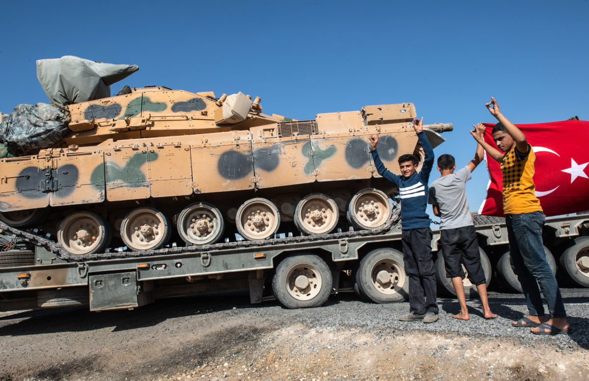 People hold up a Turkish flag as they show their support for the Turkish military during the deployment of Turkish tanks to Syria on October 12, 2019, in Akcakale, Turkey.