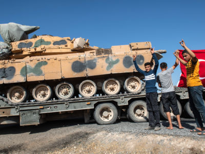 People hold up a Turkish flag as they show their support for the Turkish military during the deployment of Turkish tanks to Syria on October 12, 2019, in Akcakale, Turkey.