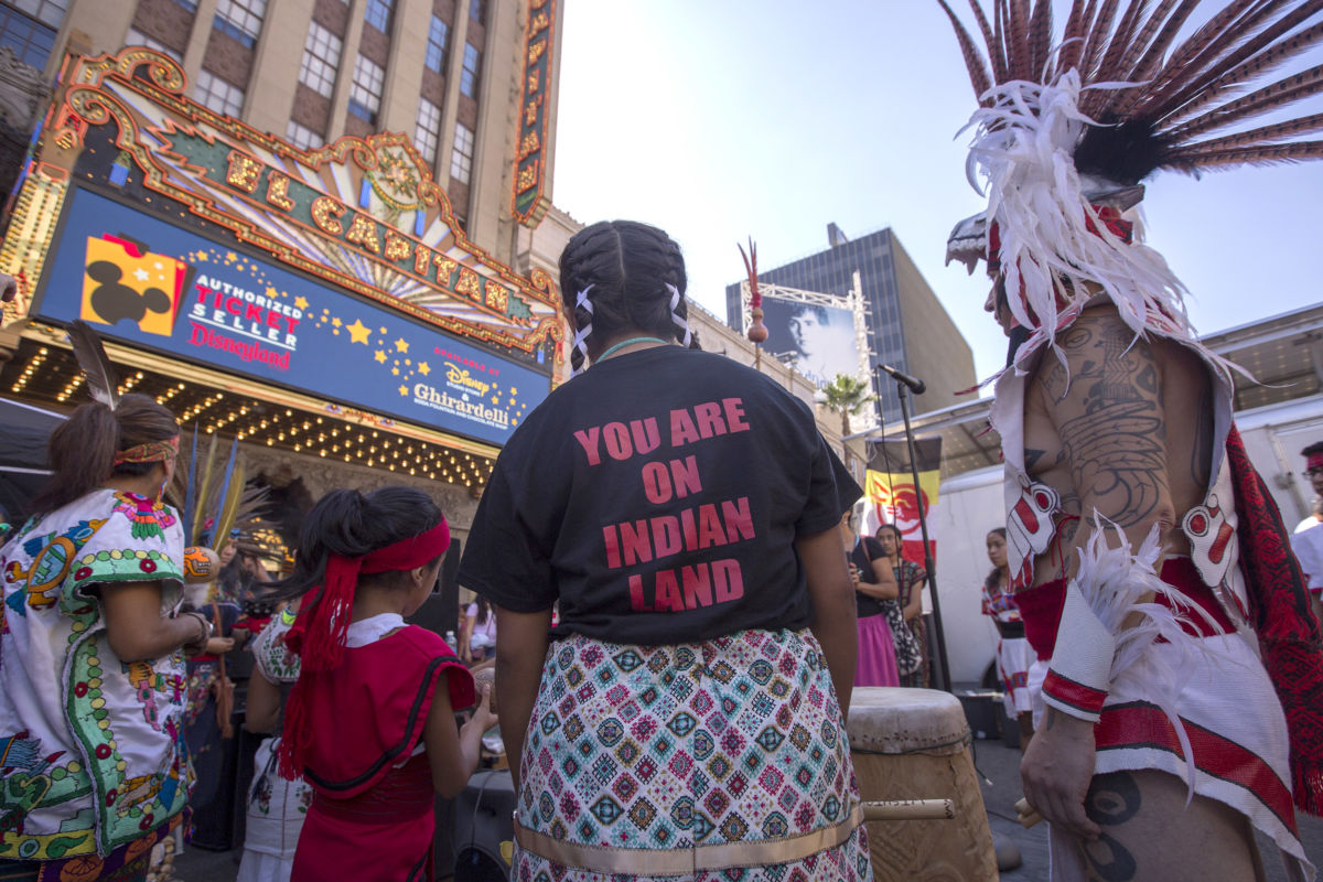 Dancers from Anahuacalmecac International University Preparatory of North America school for indigenous students pray before dancing on Hollywood Boulevard near the El Capitan Theatre during an event celebrating Indigenous Peoples' Day on October 8, 2017, in Los Angeles, California.