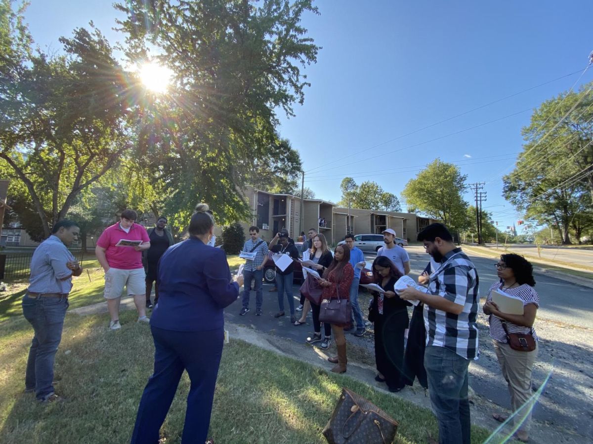 A group of local officials from around the country listen to Meredith Daye of the Durham Housing Authority speak about affordable housing in the city in front of its Liberty Street public housing development.