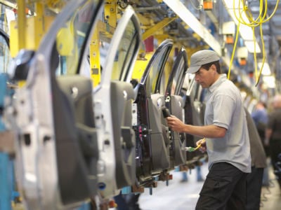 An auto worker inspects car doors in a factory