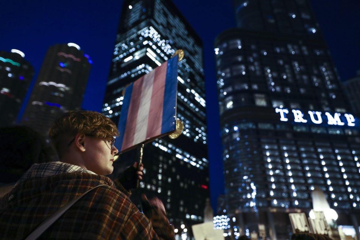 An activist holds a trans flag during a nighttime protest