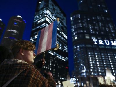 An activist holds a trans flag during a nighttime protest