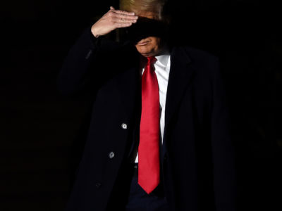 Donald Trump sheilds his eyes from a spotlght while walking in the dark