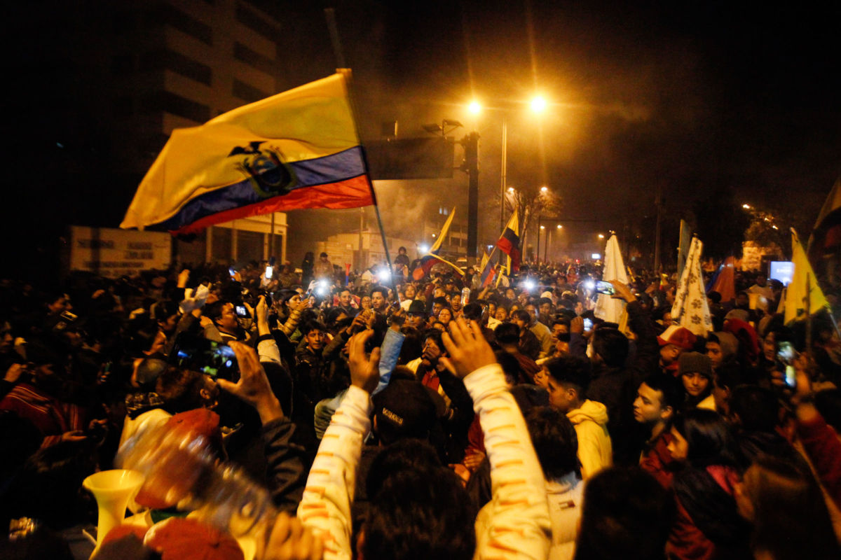 Throngs of people congregate and wave Ecuadorian flags during a protest