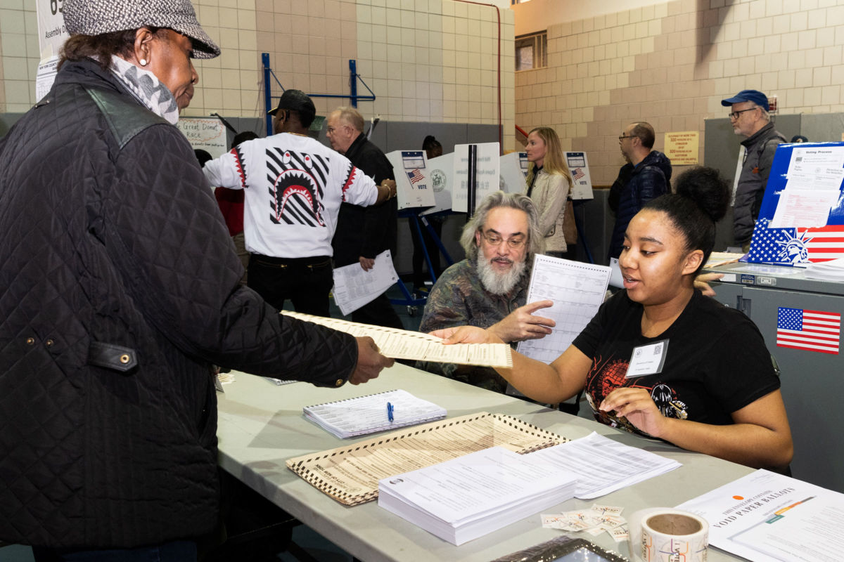 A young woman accepts the cast ballot of an older voter