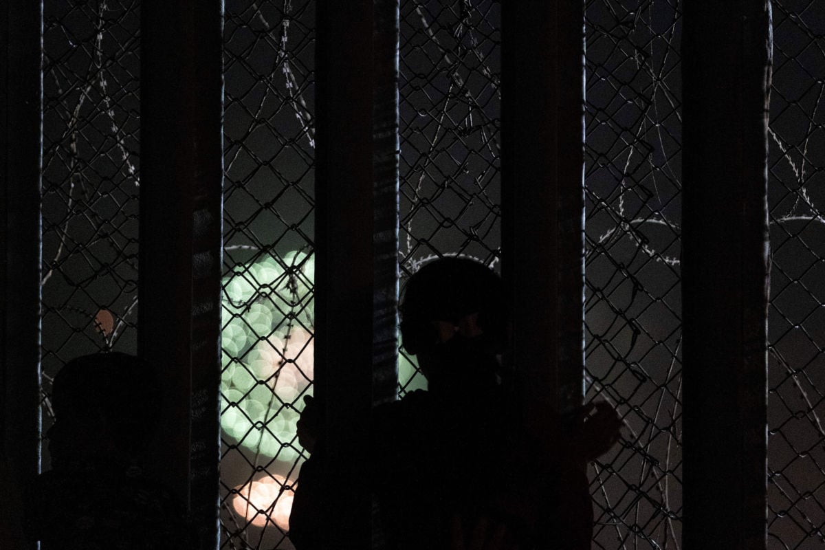 A girl looks through the U.S.-Mexico border fence from the Mexican side to watch Fourth of July fireworks being shot on the San Diego Bay, July 4, 2019.
