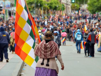 A woman holds a checkered Bolivian Indigenous flag during a massive street protest