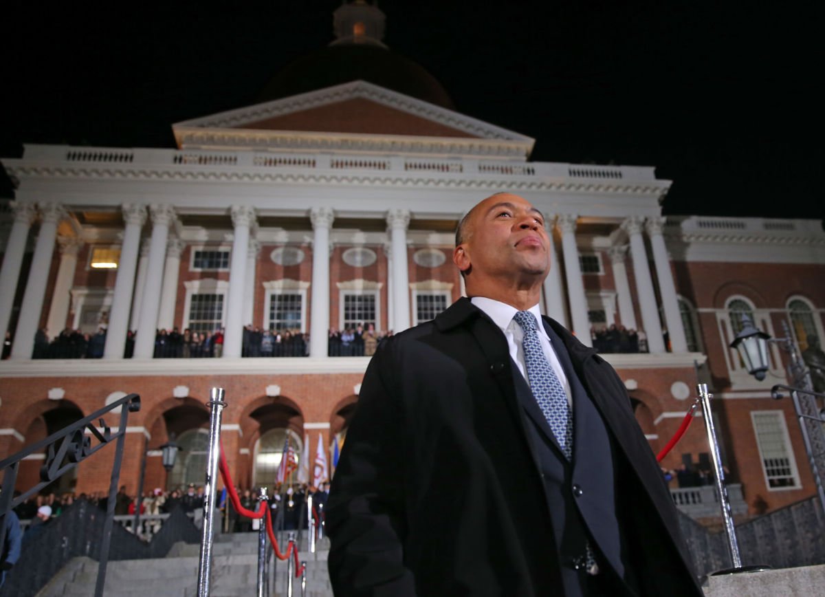 Deval Patrick stands outside a brick building with several white columns