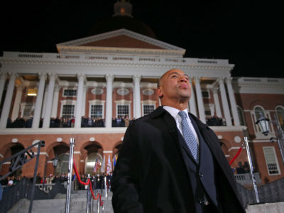 Deval Patrick stands outside a brick building with several white columns