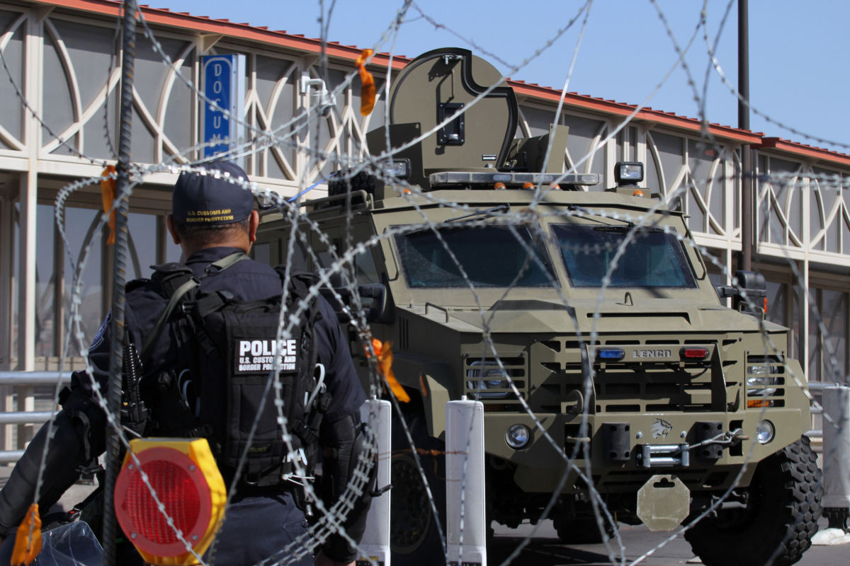 A U.S. Customs and Border Protection Office agent walks past a Border Patrol vehicle