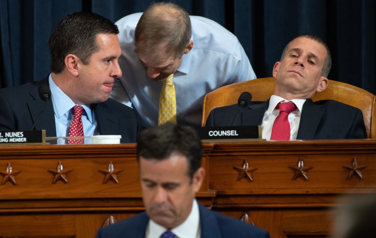 Various republicans whisper to eachother or slouch in their chairs at a podium during a hearing