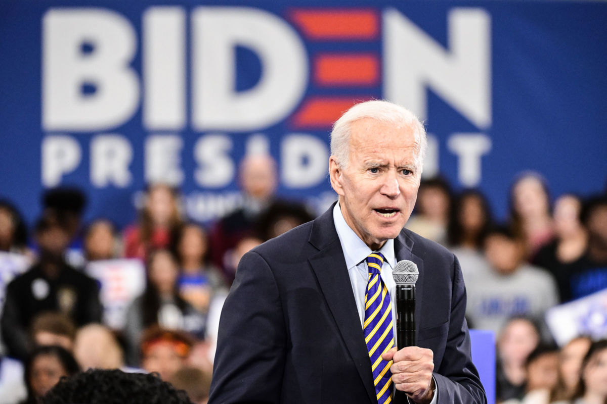 Joe Biden speaks into a microphone while looking out at a crowd