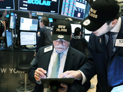 Traders wear "DOW 28,000" hats to commemorate a new record on the floor of the New York Stock Exchange on November 15, 2019.