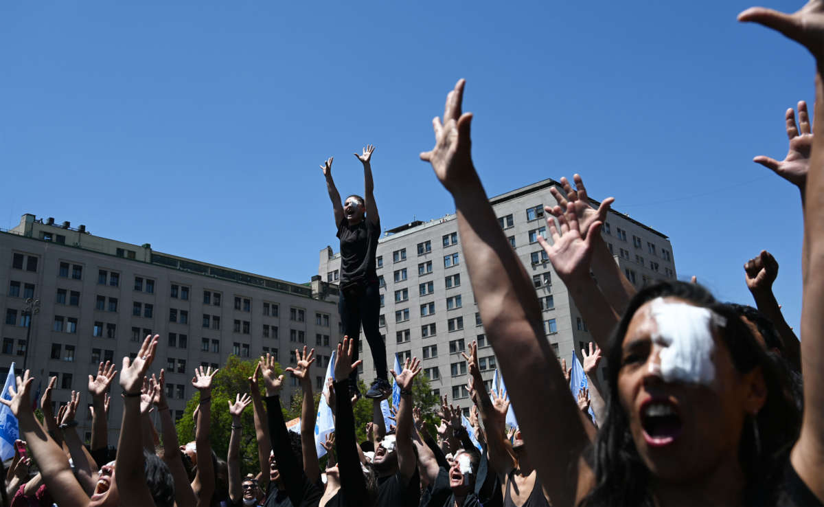 Demonstrators raise their hands in a performance against police violence outside La Moneda presidential palace in Santiago, Chile on November 12, 2019.