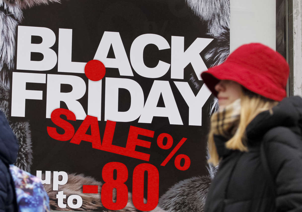 A woman in a red hat walks by an advertisement for a black friday sale