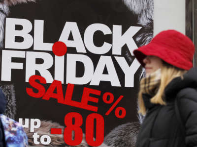 A woman in a red hat walks by an advertisement for a black friday sale