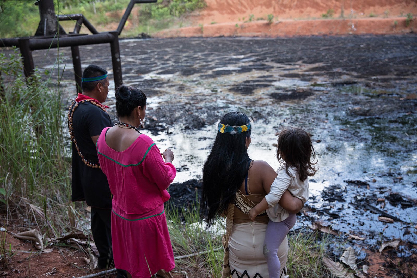 Kofan leader Emergildo Criollo, Siona leader Flor Tangoy alongside Waorani leader Nemonte Nenquimo and her daughter stand on the edge of toxic waste pit in the northern Ecuadorian Amazon.