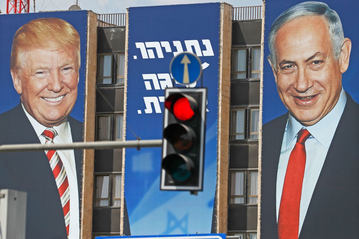 A banner depicting Trump and Netanyahu is displayed on the side of a building