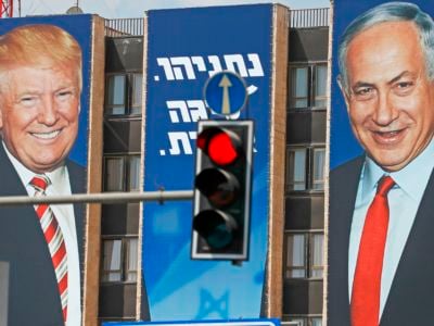 A banner depicting Trump and Netanyahu is displayed on the side of a building