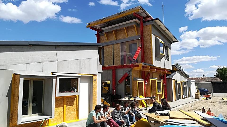 Recetas Urbanas and community members sit on the curb near Centro Sociocomunitario (Social Center) in Cañada Real Galiana, Madrid in 2019.